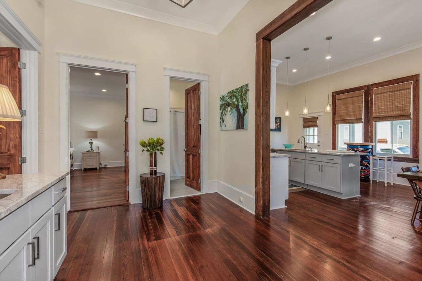 A spacious kitchen with wooden flooring, a central island, and a dining area with a table and chairs.