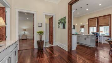 A spacious kitchen with wooden flooring, a central island, and a dining area with a table and chairs.