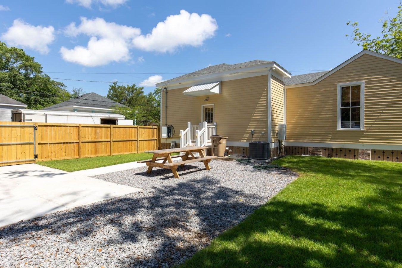 Une propriété résidentielle dotée d’un patio couvert, d’une clôture en bois et d’une allée gravillonnée.