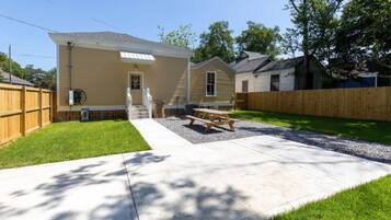 A residential property with a covered patio, a wooden fence, and a well-maintained lawn.