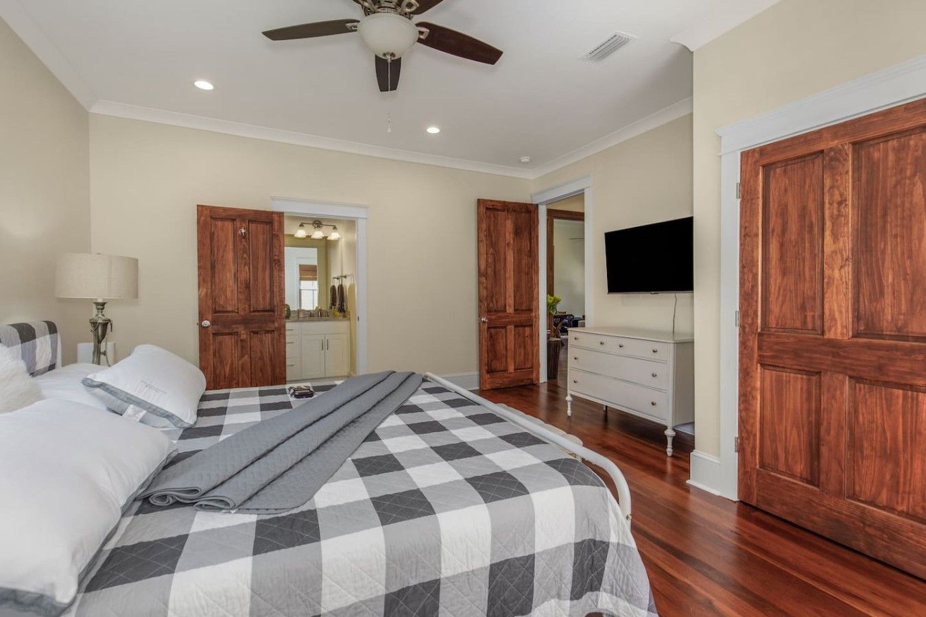 Une chambre à coucher avec un lit, une commode, un téléviseur et des portes en bois.