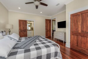 A bedroom with a bed, a dresser, a TV, and wooden doors. - Elmira in Oakleigh Garden (Mobile)