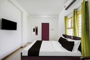 A hotel room with a bed, a flat-screen TV, a door, and a window with curtains. - Hotel O Kelambakkam Bus Terminal (Chennai)