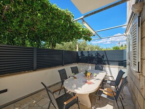 An outdoor patio with a round table, chairs, and a covered area. - Hedera Estate, House Hedera II (Dubrovnik)