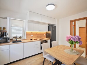 A modern kitchen with white cabinetry, a wooden countertop, a built-in oven, and a black refrigerator. - Hedera Estate, House Hedera II (Dubrovnik)