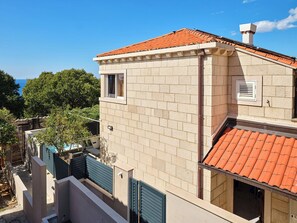 Un edificio de dos pisos con techo de tejas rojas, un ventanal pequeño y una puerta.