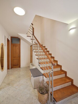 A staircase with wooden steps and metal railings, leading to a landing with a white heater and a basket of flowers. - Hedera Estate, House Hedera II (Dubrovnik)