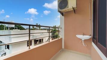 A balcony with a metal railing, a white sink, and an air conditioning unit.