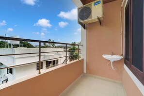 A balcony with a metal railing, a white sink, and an air conditioning unit.