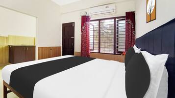 Habitación de hotel con cama, armario, ventana con cortinas, equipo de aire acondicionado y un reloj de pared.