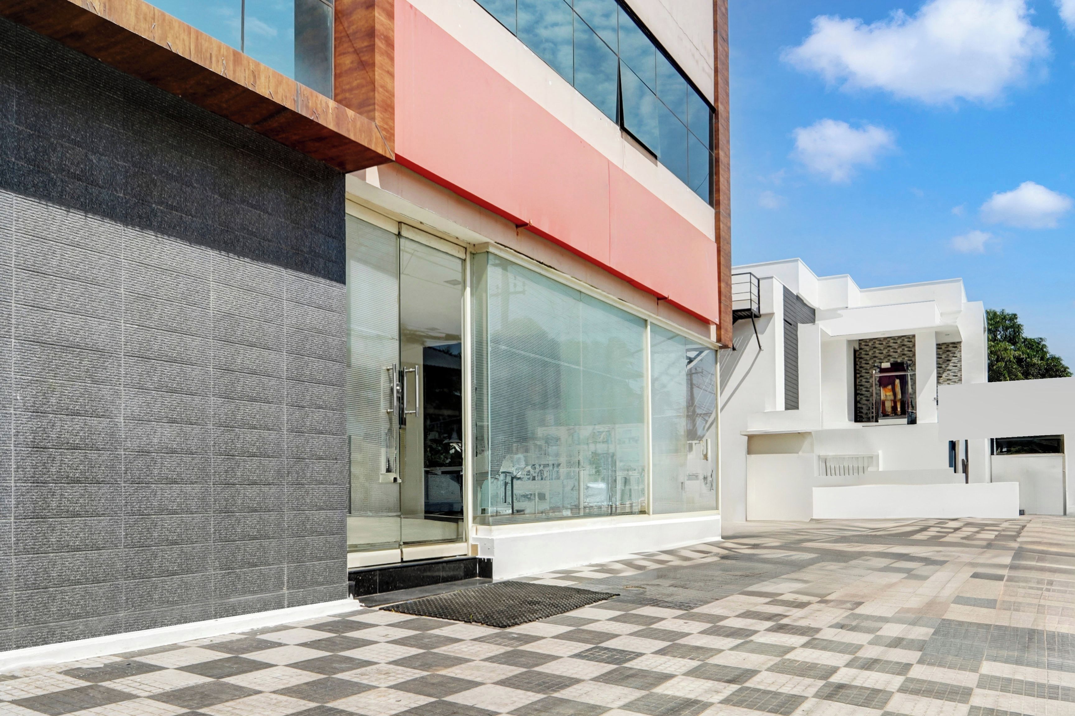 Een modern gebouw met een geruit vloermozaïek, grote glasramen en een combinatie van bakstenen en witte muren.