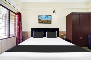 Una habitación de hotel con una cama, una mesita de noche, un cuadro y un armario.