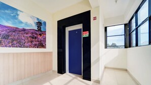 A hallway with a blue door, a fire exit sign, and a large window.
