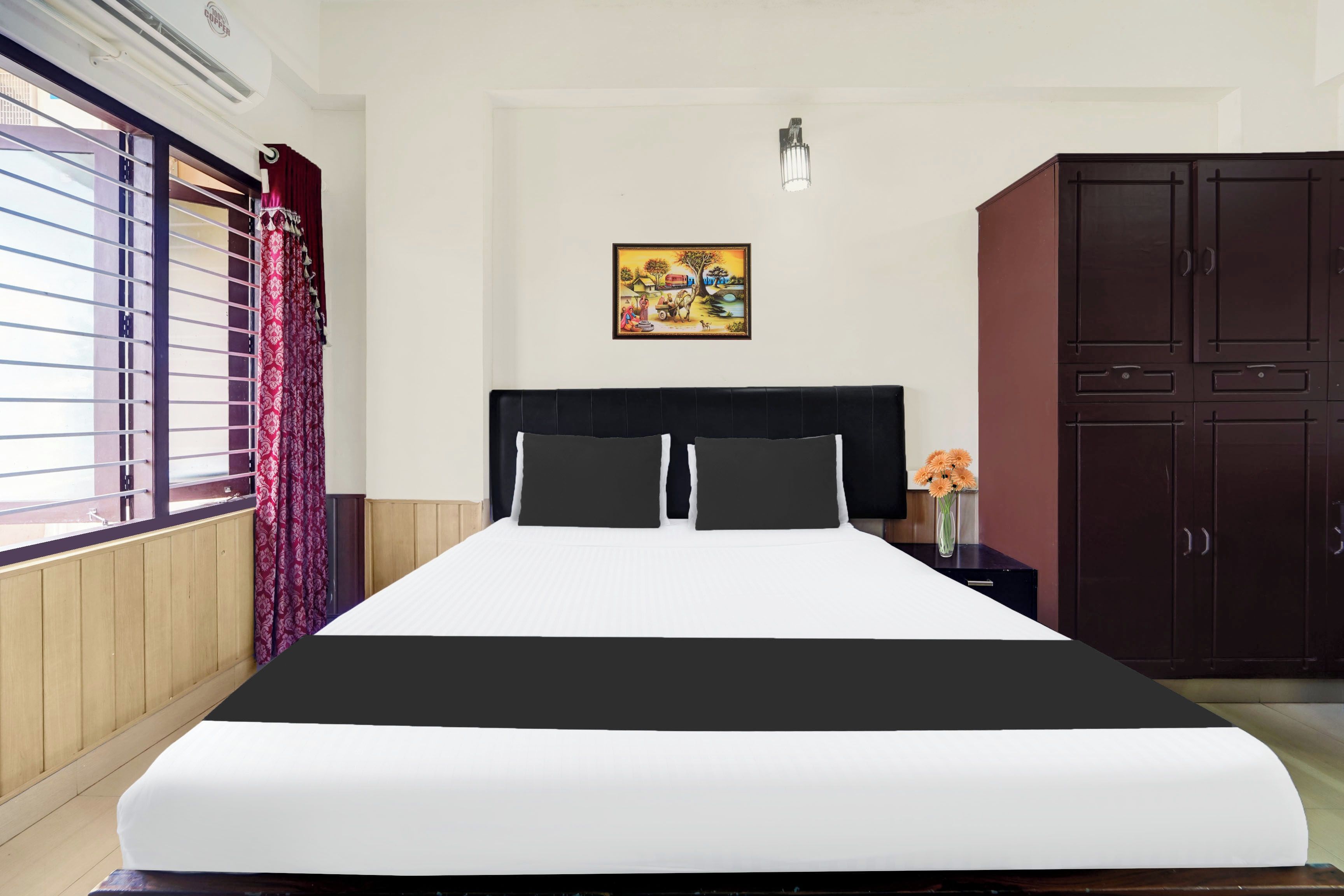Une chambre d’hôtel comprenant un lit, une table de chevet, une armoire, une fenêtre avec des rideaux et un luminaire fixé au mur.