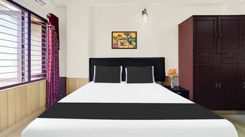 Une chambre d’hôtel comprenant un lit, une table de chevet, une armoire, une fenêtre avec des rideaux et un luminaire fixé au mur.