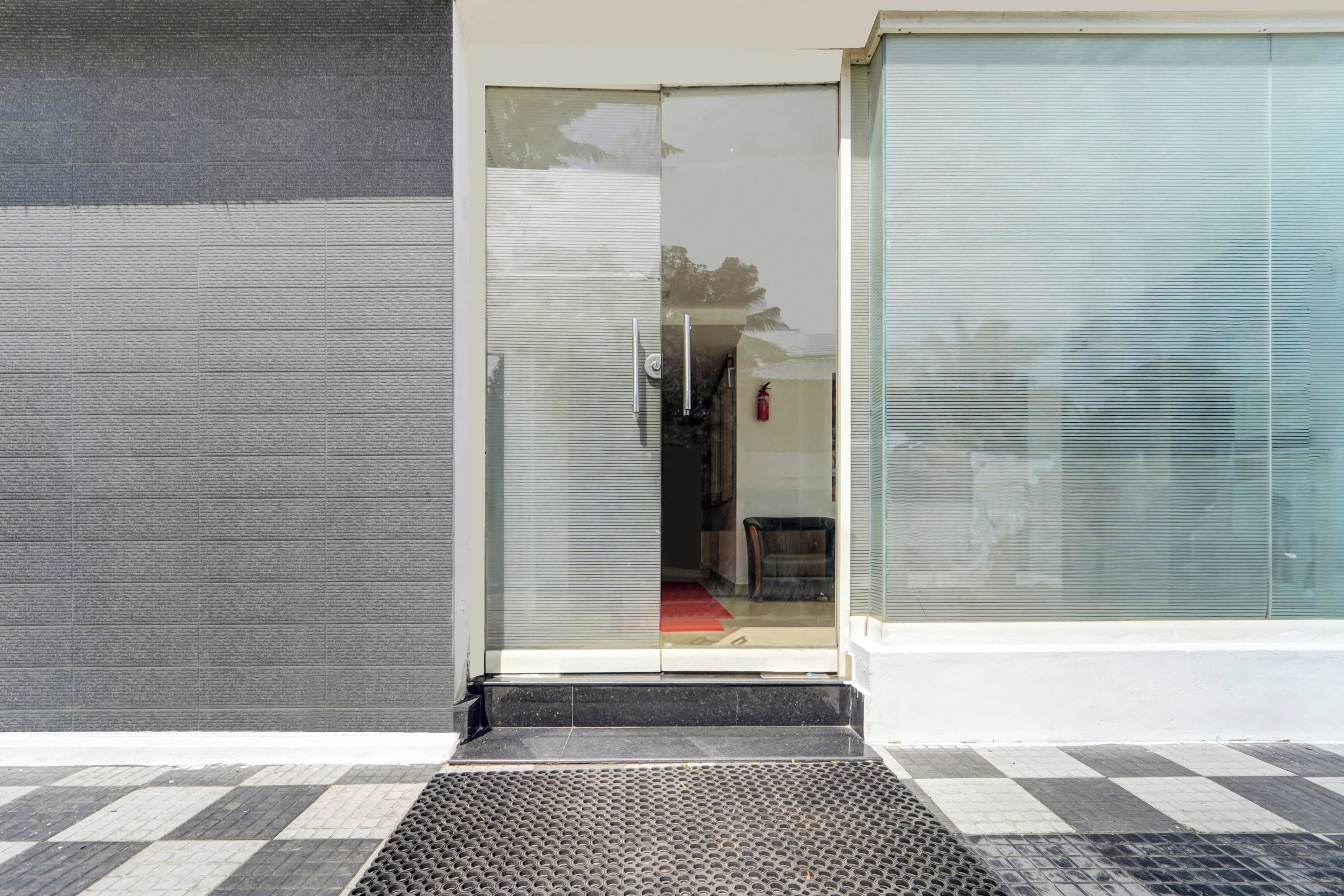 A building entrance with a glass door, a fire extinguisher, and a metal step leading up to the door.