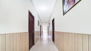 A corridor with wooden paneling on the walls, a tiled floor, and doors on both sides.
