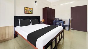 Una habitación de hotel con cama, escritorio, armario y un cuadro en la pared.