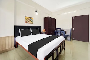 Een hotelkamer met een bed, een bureau, een kledingkast en een schilderij aan de muur.