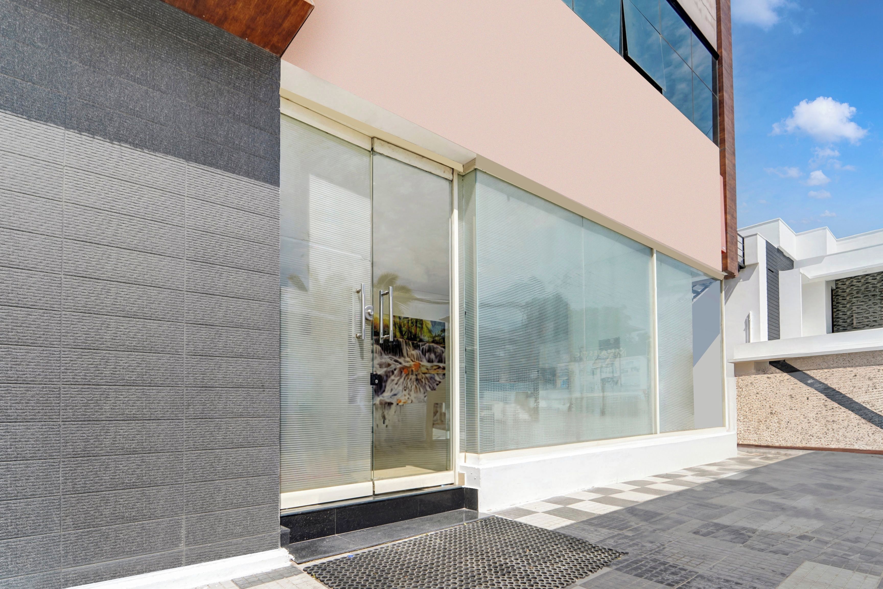 A modern building with large glass windows, a metal door, and a checkered floor pattern.