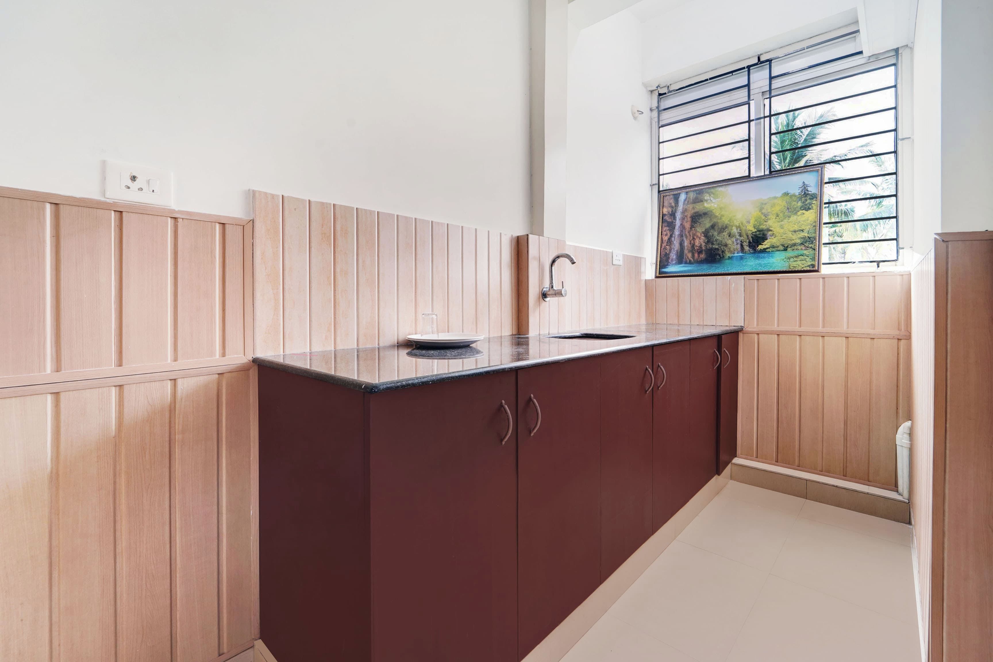 Una cocina con armarios de madera, una encimera y una ventana con vistas al verdor.