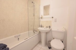 A bathroom with a bathtub, a sink, a toilet, and a glass-enclosed shower area. - Uncle Bill`s Cottage (Thongsbridge)