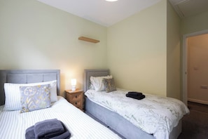 A double bed with a striped bedspread and a pillow with a floral pattern. - Uncle Bill`s Cottage (Thongsbridge)
