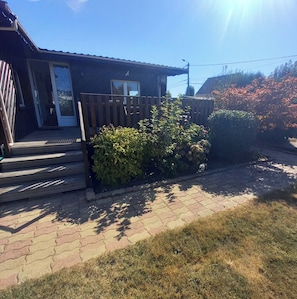 A residential building with a wooden deck, a front door, and a small porch.