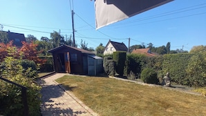 A paved pathway leading to a house with a small shed and a well-maintained lawn. - A Little Paradise (Sanghen)