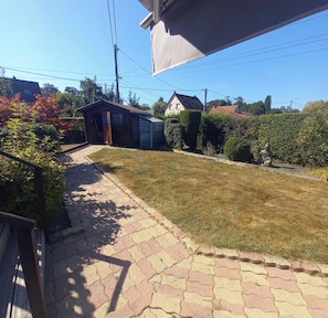 A paved pathway leading to a house with a small shed and a well-maintained lawn. - A Little Paradise (Sanghen)