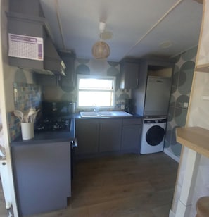 A compact kitchen with a sink, stove, and a washing machine.