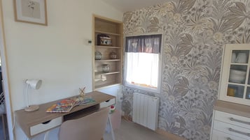 Een kamer met een bureau, stoel, radiator en een raam met gordijnen.