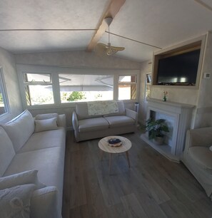 A living room with a sofa, a coffee table, a fireplace, and a television mounted above it.