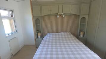 Een slaapkamer met een bed, een raam en inbouwkasten.