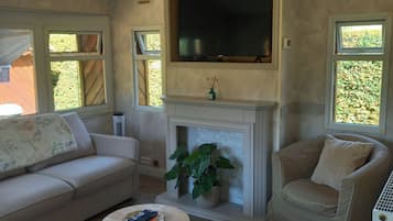 Un salon avec un canapé, un fauteuil et une petite table sur laquelle se trouve une télécommande.