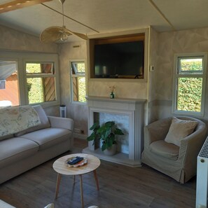 A living room with a sofa, armchair, and a small table with a remote control.
