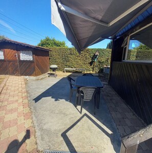 A patio area with a table and chairs, a barbecue grill, and a covered seating area.