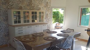 A dining area with a table, chairs, and a cabinet with glass doors. - A Little Paradise (Sanghen)