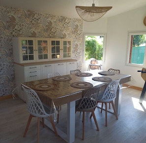 A dining area with a table, chairs, and a cabinet with glass doors. - A Little Paradise (Sanghen)