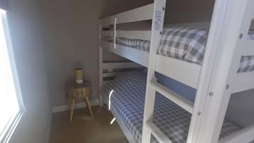 A bunk bed room with a small table and a lamp.