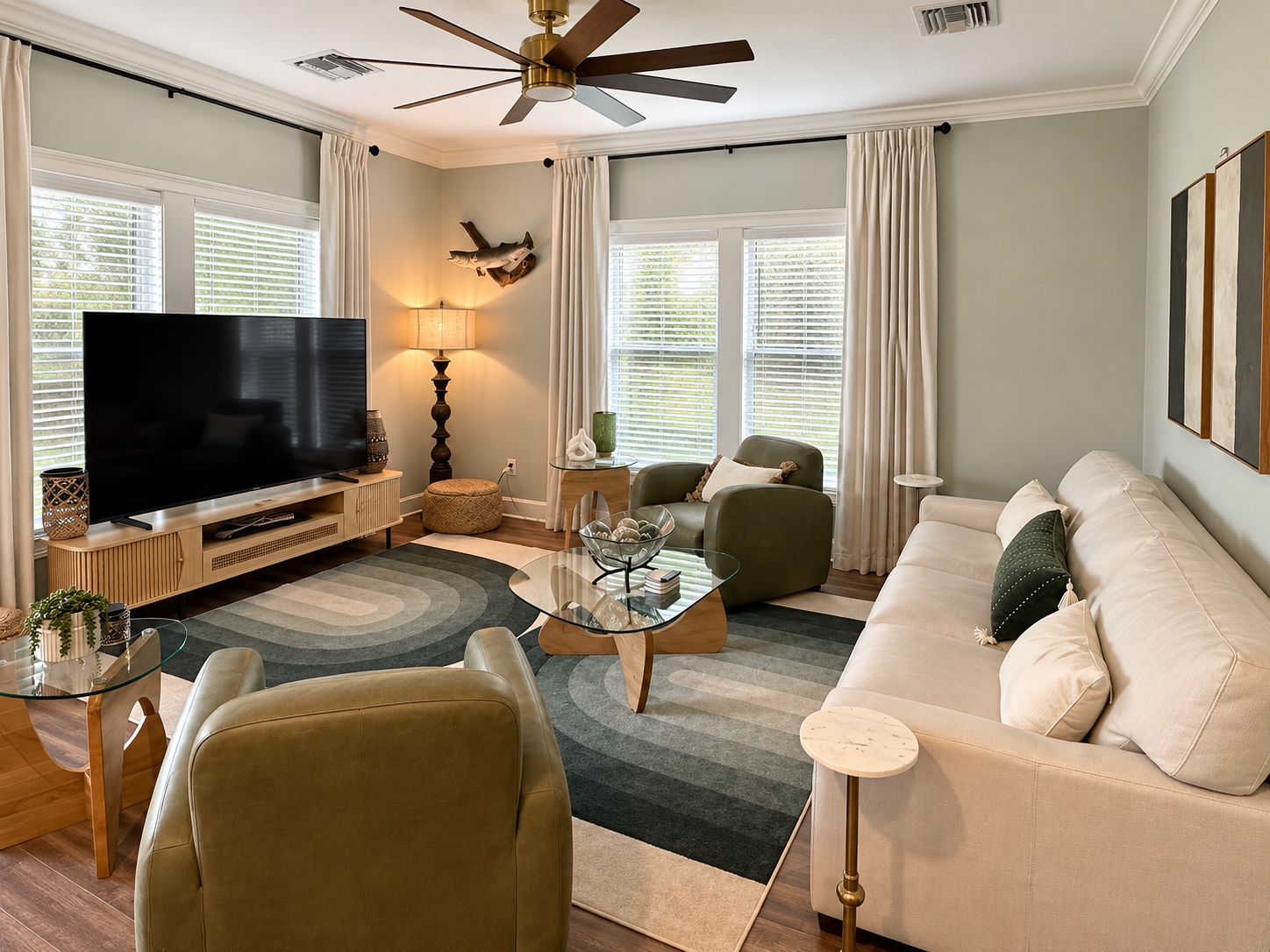 A modern living room with a flat-screen TV, a ceiling fan, and a sofa.