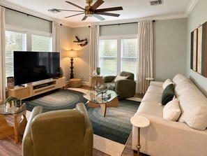 Un salon moderne doté d’un téléviseur à écran plat, d’un ventilateur de plafond et d’un canapé.