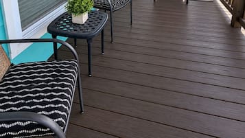 A covered porch with outdoor furniture, a sliding door, and a view of the landscape.
