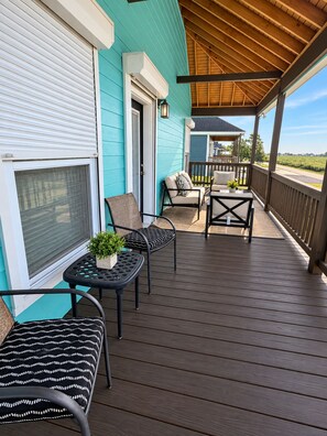 Un porche cubierto con mobiliario exterior, una puerta corrediza y vista al paisaje.