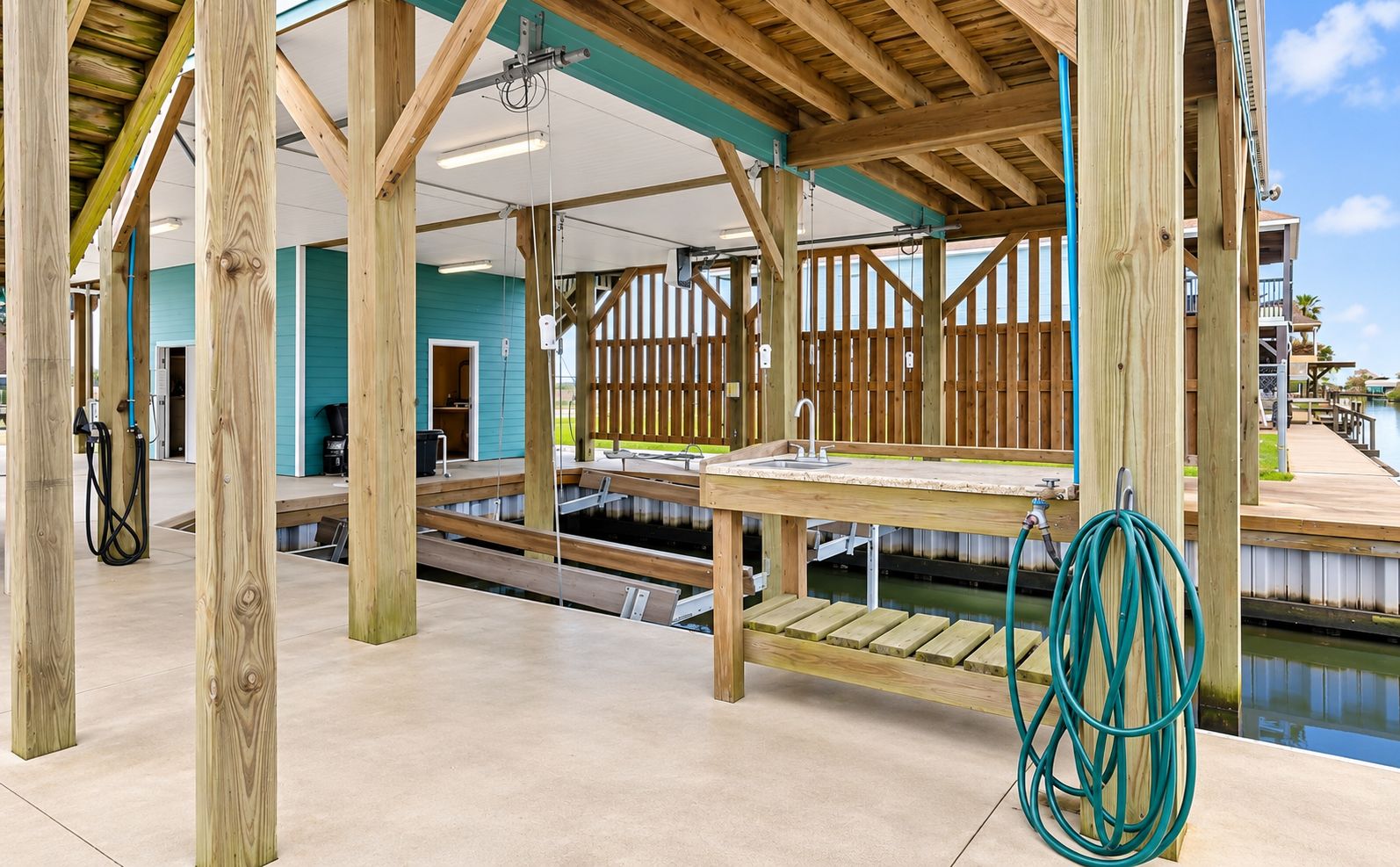 A wooden deck with a pool table, a hose, and a wooden structure with a view of a building in the background.