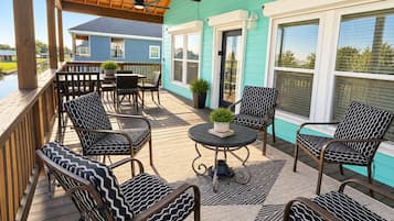 Eine überdachte Terrasse mit Sitzgelegenheiten und Deckenventilator.