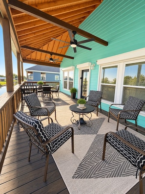 Une terrasse extérieure couverte, dotée de sièges et d’un ventilateur de plafond.