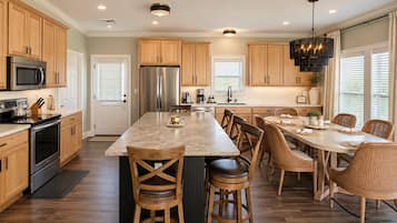 Una cocina moderna con armarios de madera, electrodomésticos de acero inoxidable, una isla central y un comedor con sillas de mimbre.