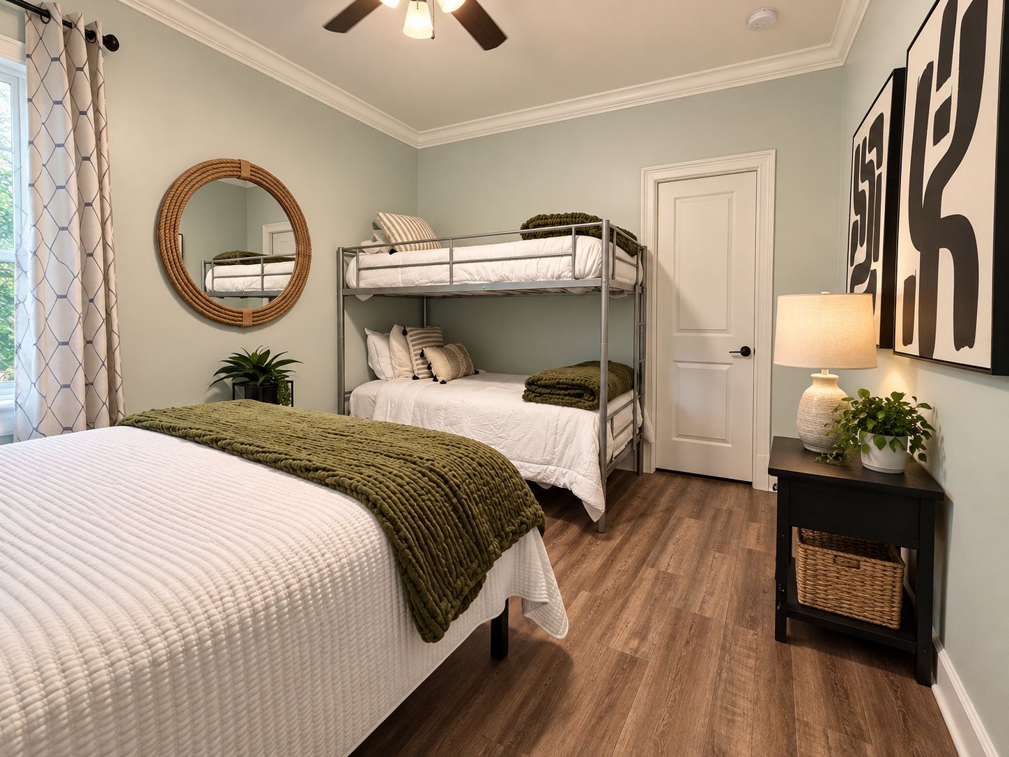 A bedroom with bunk beds, a round mirror, a bedside table with a lamp, and a door.