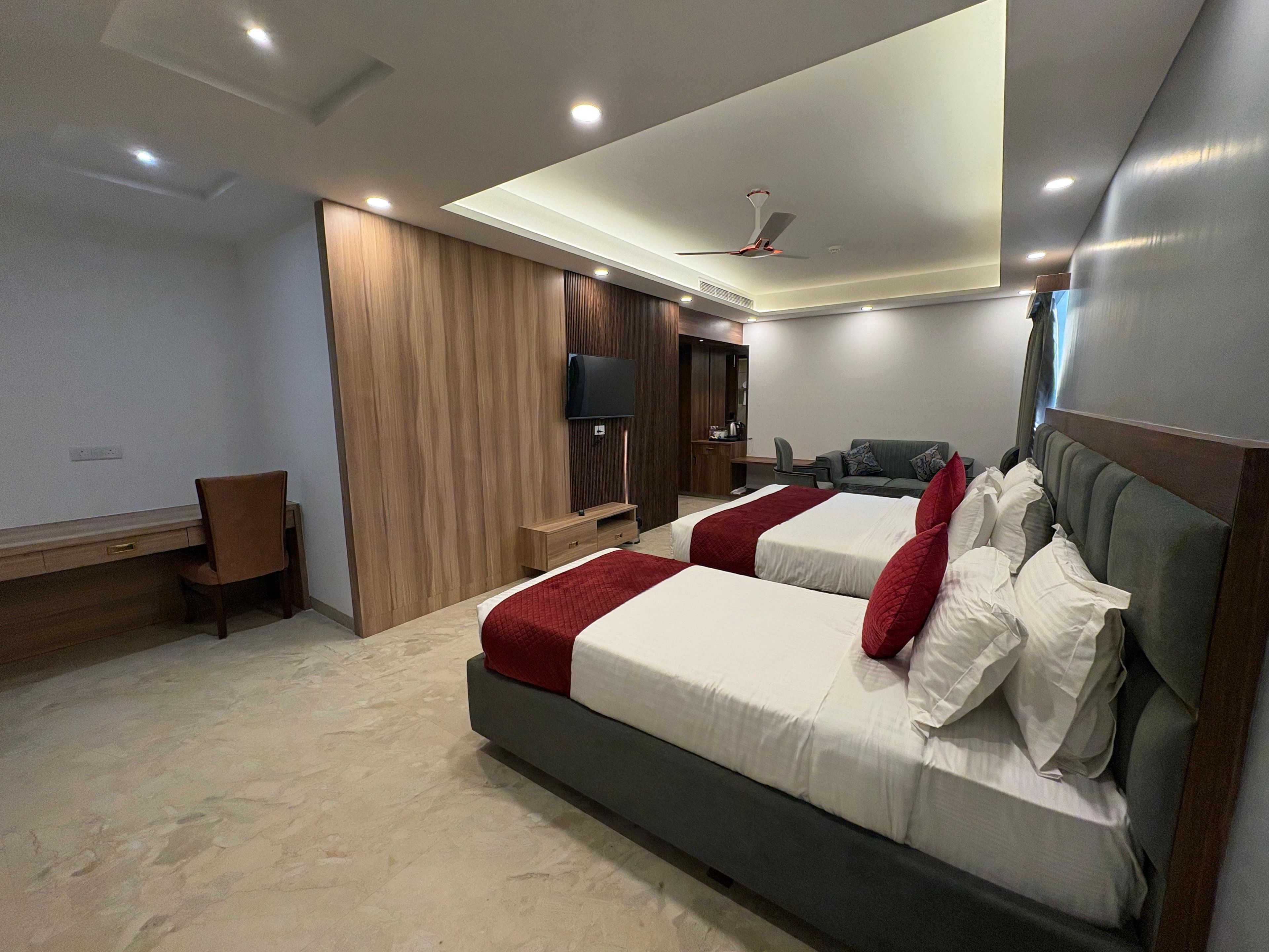 Habitación de hotel con dos camas, un escritorio, una silla, un televisor y un armario.